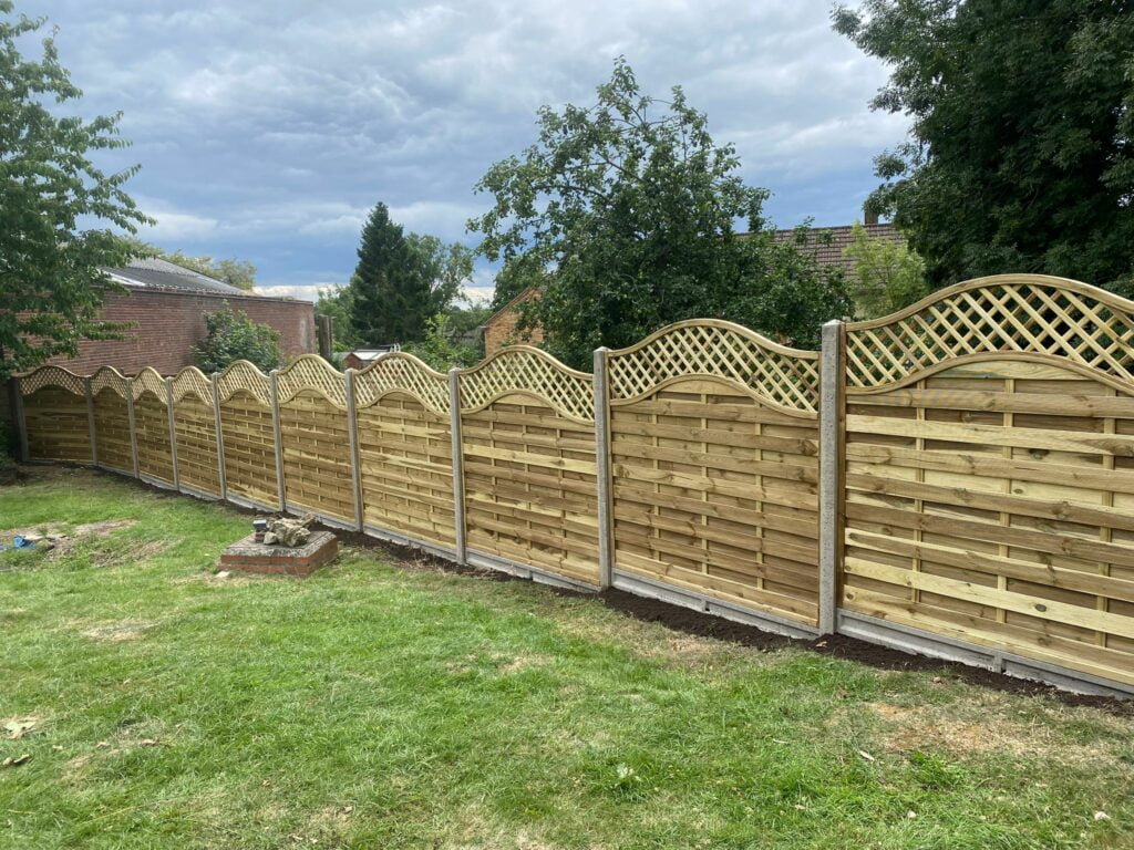 A garden showing newly installed decorative fence panels There are a total of 10 wooden fence panels installed with concrete posts and grave boards