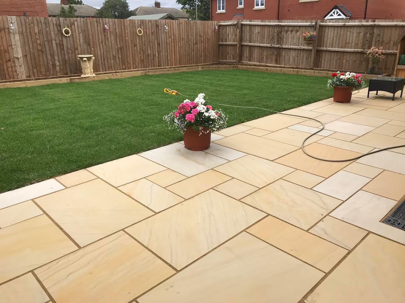 An image showing a newly renovated back garden, includes new real turf and patio.